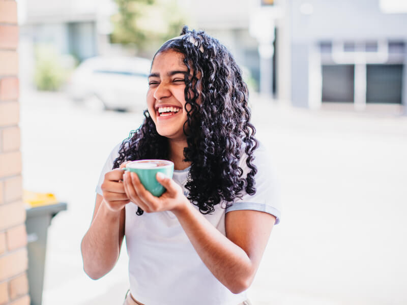 Girl laughing holding a mug of coffee
